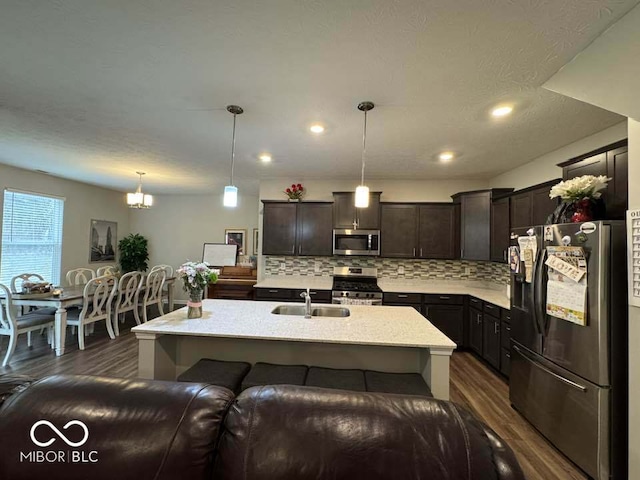 kitchen with backsplash, stainless steel appliances, dark brown cabinetry, and dark wood finished floors