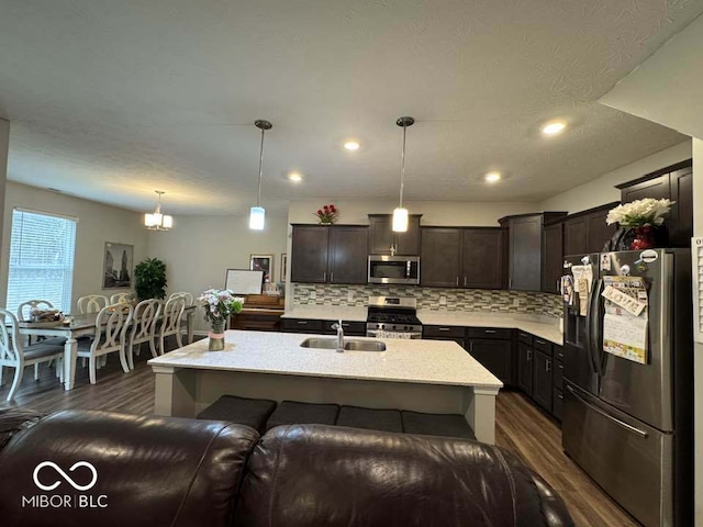 kitchen featuring dark wood finished floors, a sink, backsplash, and appliances with stainless steel finishes