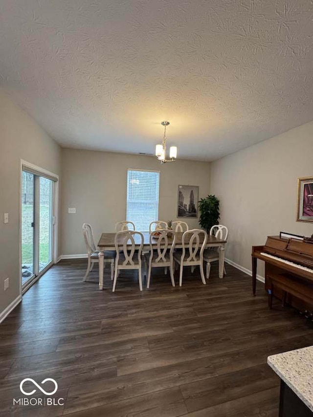 dining area featuring baseboards, dark wood-style flooring, a textured ceiling, and a notable chandelier