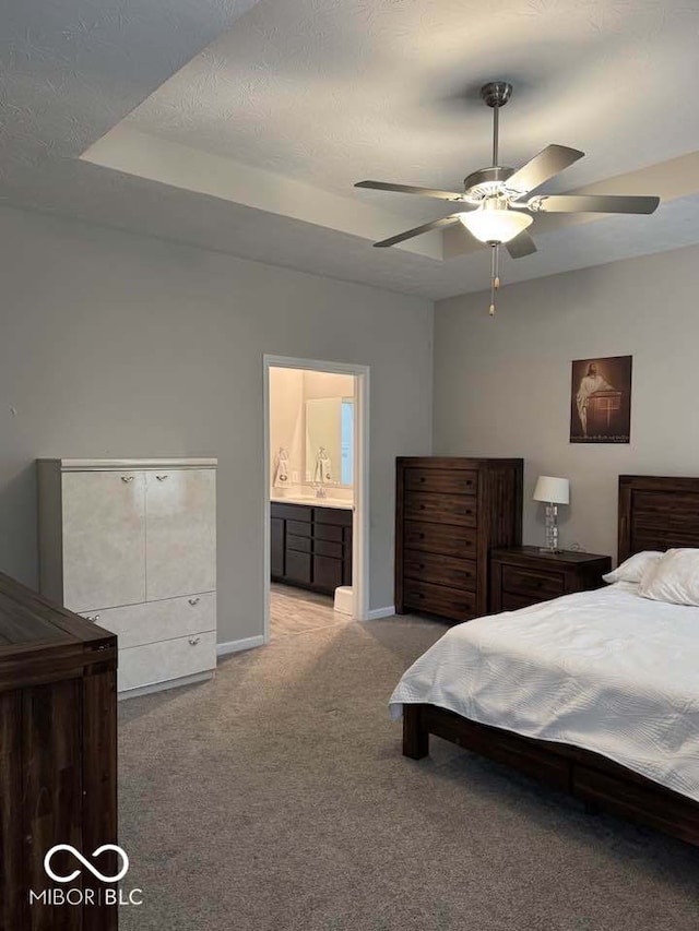 bedroom featuring a textured ceiling, baseboards, connected bathroom, light carpet, and a sink