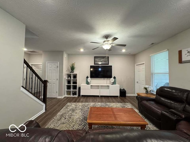 living area with baseboards, wood finished floors, ceiling fan, and stairway