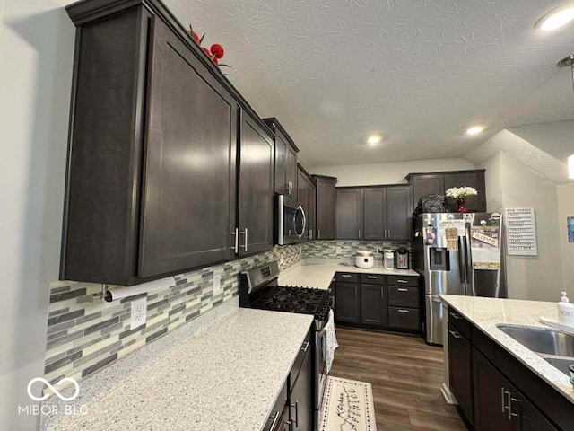 kitchen featuring a textured ceiling, dark wood finished floors, dark brown cabinetry, tasteful backsplash, and appliances with stainless steel finishes