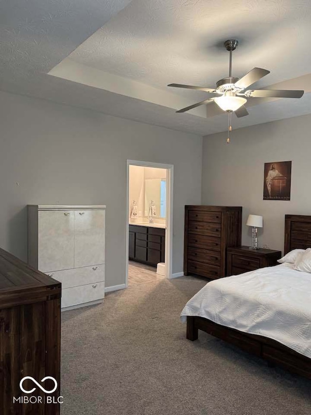 bedroom featuring carpet floors, a sink, a textured ceiling, ensuite bathroom, and baseboards