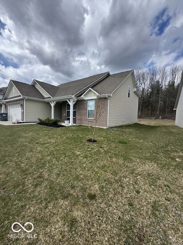 ranch-style home featuring a front yard, a garage, brick siding, and roof with shingles