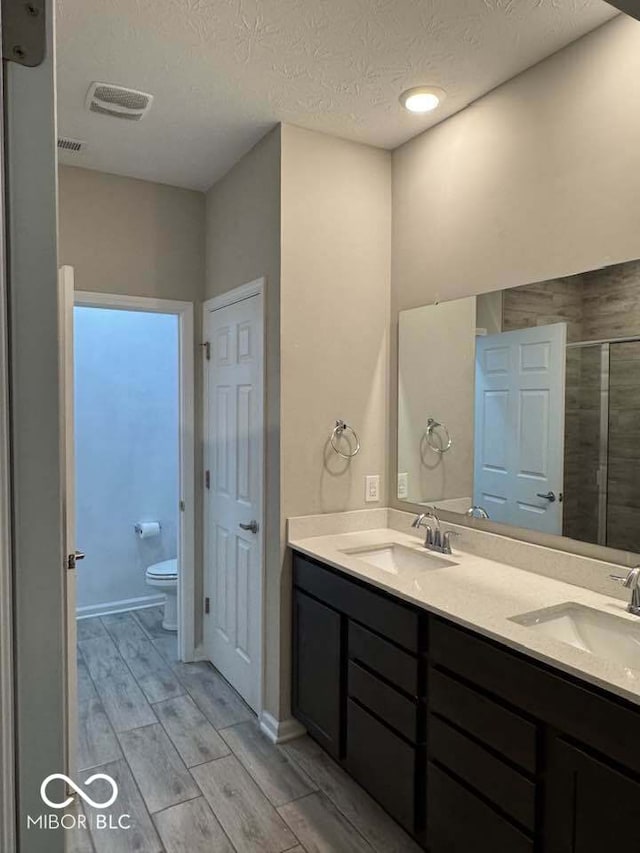 bathroom featuring toilet, a sink, visible vents, and wood tiled floor