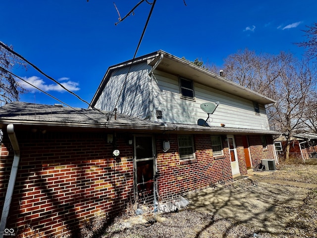 rear view of house featuring brick siding, central air condition unit, and a patio