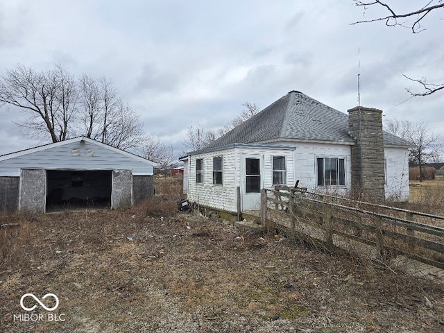 view of property exterior with an outbuilding, roof with shingles, and fence