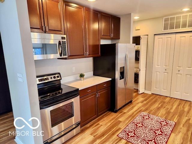 110 E Washington St Unit 802, Indianapolis, IN 46204 - kitchen featuring appliances with stainless steel finishes, estacked washer and dryer, light countertops, light wood-style floors, and recessed lighting