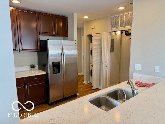 110 E Washington St Unit 802, Indianapolis, IN 46204 - kitchen with stainless steel fridge, light wood-style flooring, recessed lighting, light stone countertops, and dark brown cabinetry
