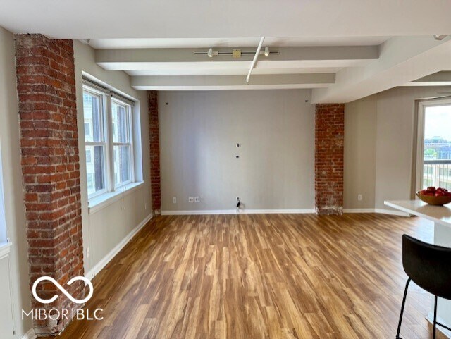 110 E Washington St Unit 802, Indianapolis, IN 46204 - unfurnished living room featuring wood finished floors, plenty of natural light, and beamed ceiling