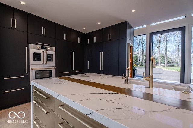 395 Breakwater Dr, Fishers, IN 46037 - kitchen featuring recessed lighting, light stone countertops, dark cabinetry, and stainless steel double oven