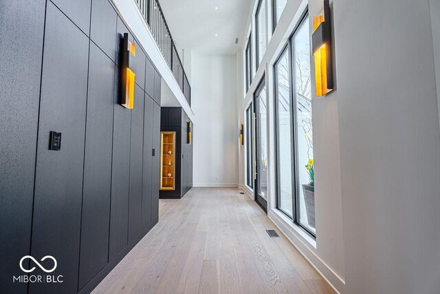 395 Breakwater Dr, Fishers, IN 46037 - hallway with light wood-style flooring, a towering ceiling, baseboards, and visible vents