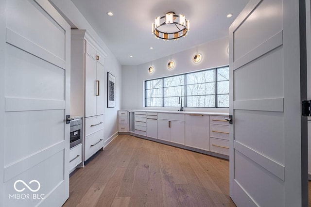 395 Breakwater Dr, Fishers, IN 46037 - kitchen with light countertops, a sink, white cabinetry, light wood-style floors, and recessed lighting