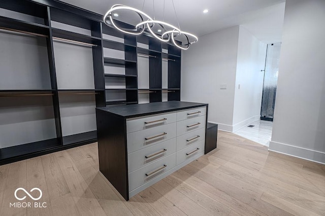 395 Breakwater Dr, Fishers, IN 46037 - walk in closet featuring light wood-type flooring and an inviting chandelier