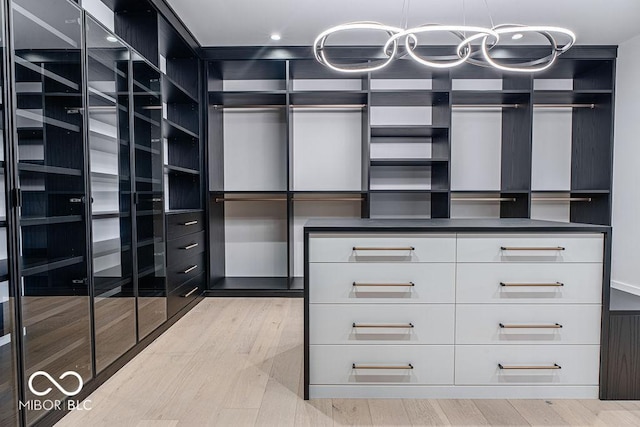 395 Breakwater Dr, Fishers, IN 46037 - walk in closet featuring light wood finished floors and an inviting chandelier