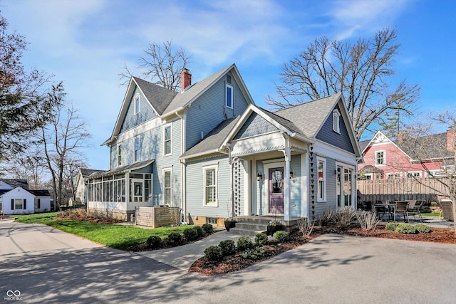 450 W Ash St, Zionsville, IN 46077 - view of front of house featuring a chimney, fence, a sunroom, and roof with shingles