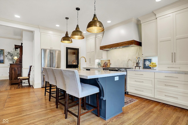 450 W Ash St, Zionsville, IN 46077 - kitchen with custom exhaust hood, high quality appliances, an island with sink, and light wood-type flooring