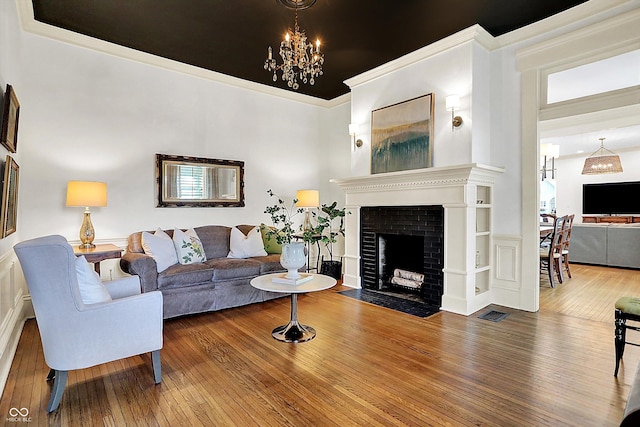 450 W Ash St, Zionsville, IN 46077 - living area with visible vents, a notable chandelier, ornamental molding, a fireplace, and hardwood / wood-style floors