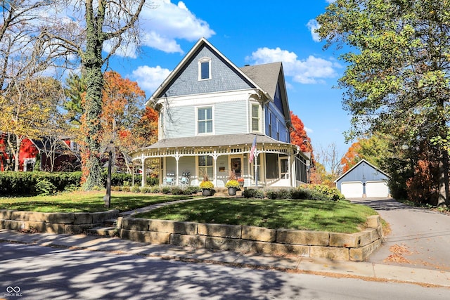 450 W Ash St, Zionsville, IN 46077 - victorian home featuring a front yard, a detached garage, a porch, aphalt driveway, and an outbuilding