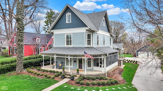 450 W Ash St, Zionsville, IN 46077 - victorian home with a sunroom, roof with shingles, a patio, and a front lawn