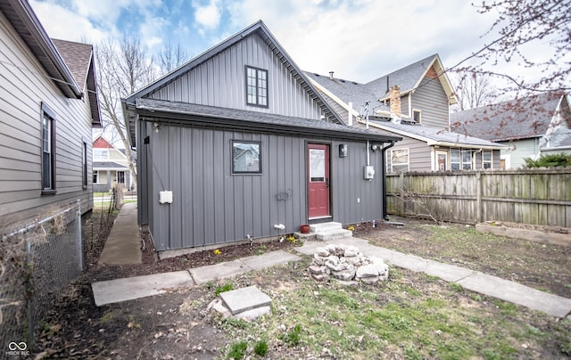 back of house with board and batten siding, a shingled roof, fence, and entry steps