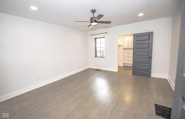 unfurnished bedroom featuring baseboards, visible vents, a walk in closet, and dark wood finished floors