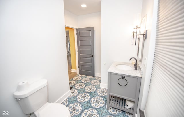 bathroom with toilet, vanity, baseboards, and recessed lighting
