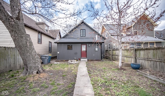 back of house featuring a fenced backyard and roof with shingles