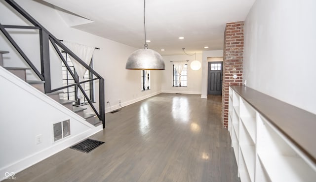 unfurnished dining area with stairs, visible vents, baseboards, and dark wood-type flooring