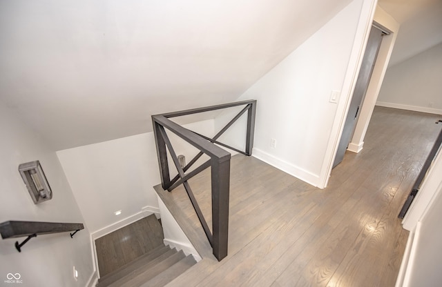 staircase with baseboards, vaulted ceiling, and wood finished floors