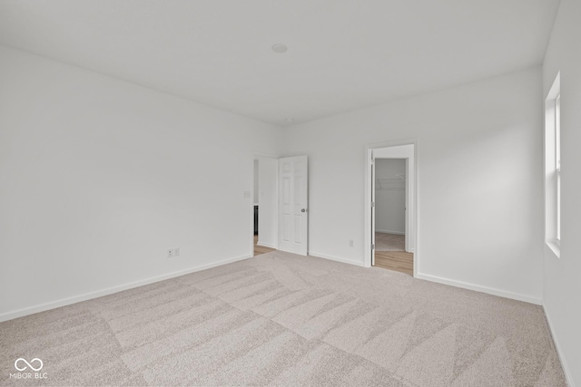 unfurnished bedroom with carpet floors, a walk in closet, baseboards, and a closet