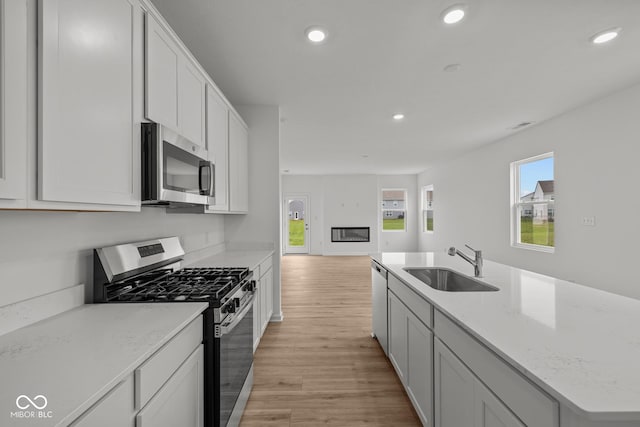 kitchen featuring stainless steel appliances, a sink, light wood-type flooring, recessed lighting, and plenty of natural light