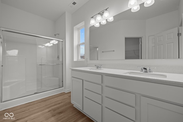 full bathroom featuring a shower stall, wood finished floors, and double vanity