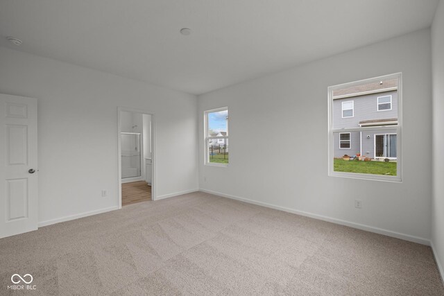 unfurnished bedroom featuring carpet flooring, multiple windows, and baseboards