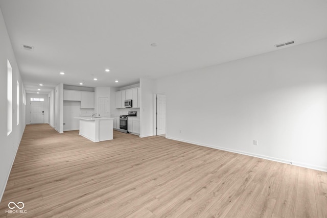 unfurnished living room featuring recessed lighting, light wood-type flooring, and baseboards