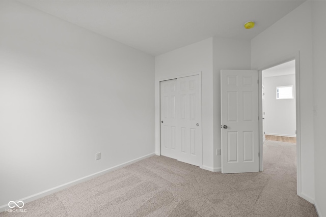 unfurnished bedroom featuring carpet flooring, baseboards, and a closet