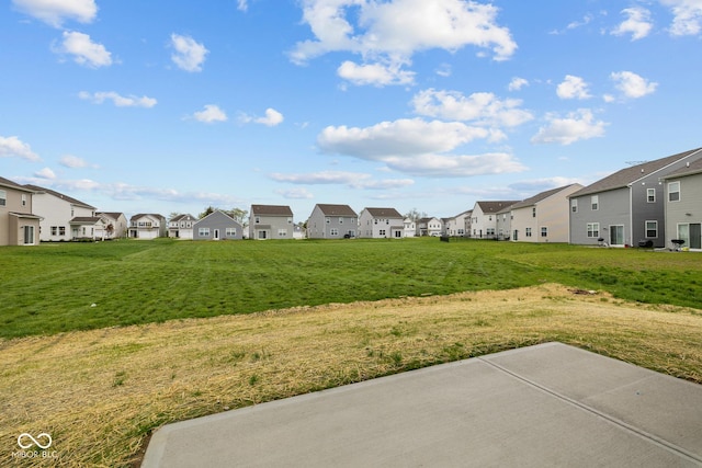 view of green lawn featuring a residential view and a patio