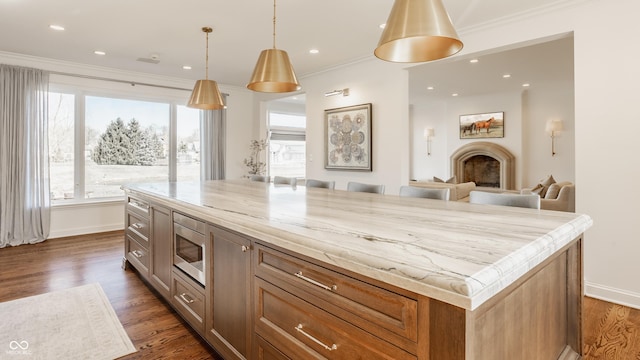 kitchen featuring stainless steel microwave, crown molding, dark wood-style flooring, light stone counters, and baseboards