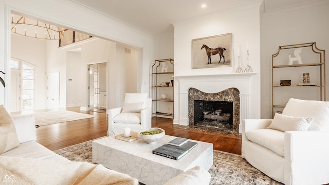 living area featuring wood finished floors, ornamental molding, a premium fireplace, a chandelier, and recessed lighting