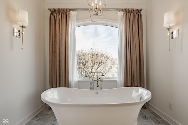 full bath with marble finish flooring, baseboards, and a freestanding tub
