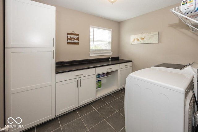 clothes washing area featuring independent washer and dryer, cabinet space, and dark tile patterned flooring