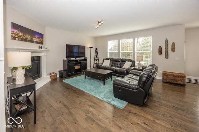 living area with hardwood / wood-style flooring, a glass covered fireplace, and baseboards