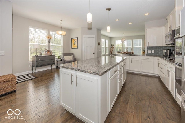 kitchen with stainless steel appliances, a center island, dark wood-style flooring, recessed lighting, and white cabinetry