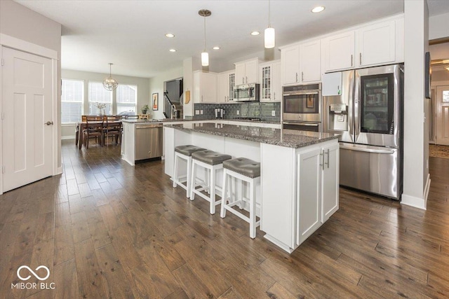 kitchen featuring stainless steel appliances, a peninsula, dark wood-style flooring, a kitchen island, and recessed lighting