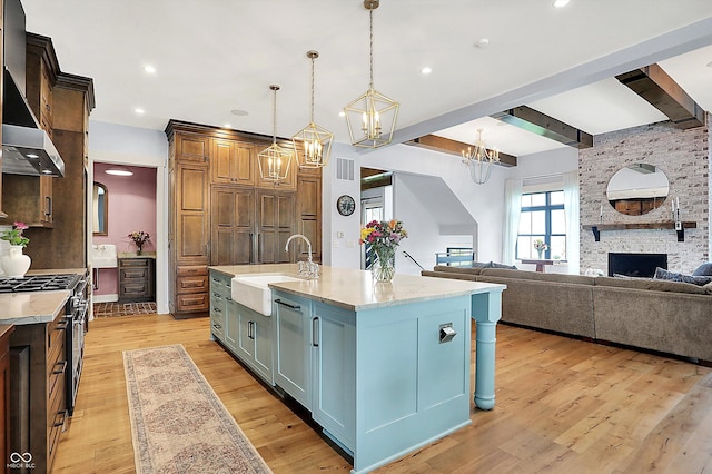 5120 Melbourne Pl, Zionsville, IN 46077 - kitchen featuring a sink, stainless steel gas range oven, wall chimney range hood, light wood-type flooring, and pendant lighting