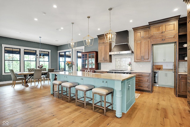 5120 Melbourne Pl, Zionsville, IN 46077 - kitchen featuring wall chimney exhaust hood, a chandelier, a large island with sink, wine cooler, and decorative backsplash