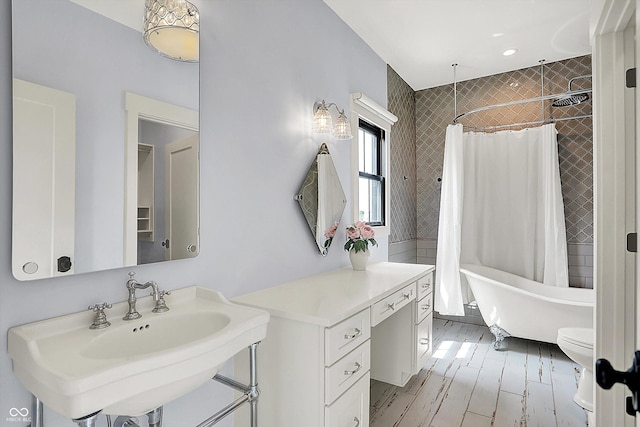 5120 Melbourne Pl, Zionsville, IN 46077 - bathroom featuring a freestanding tub, a sink, a shower with shower curtain, wood finished floors, and toilet