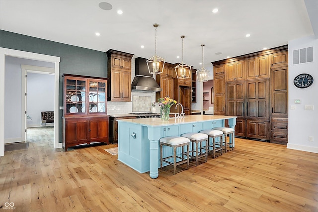 5120 Melbourne Pl, Zionsville, IN 46077 - kitchen with wall chimney range hood, light wood-style floors, light countertops, backsplash, and recessed lighting