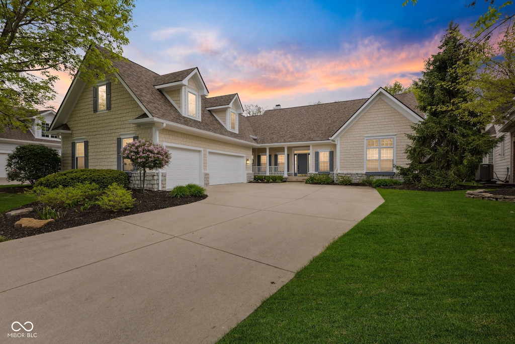 view of front of home with a garage, driveway, a shingled roof, and a yard