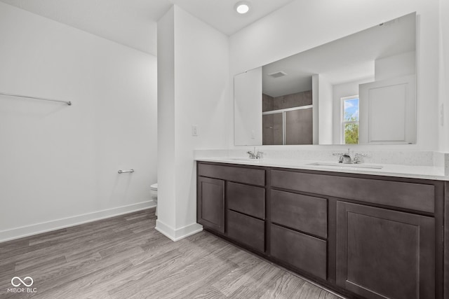 3913 Highcrest Rd, Indianapolis, IN 46239 - full bathroom featuring a stall shower, toilet, double vanity, baseboards, and wood finished floors